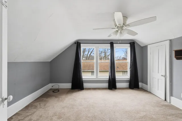 an empty room with chandelier fan and windows