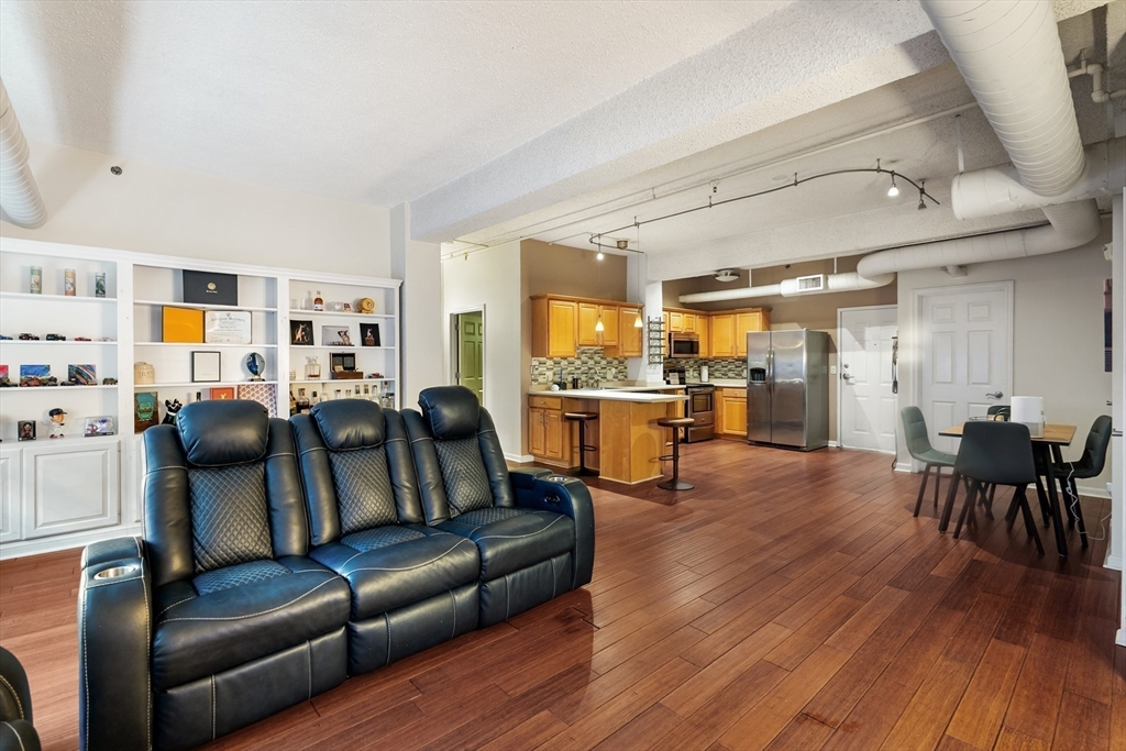 a living room with furniture wooden floor and kitchen view
