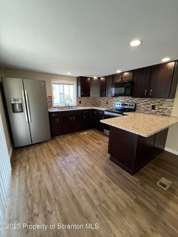 a large kitchen with stainless steel appliances granite countertop a large counter top a stove a microwave a sink and a refrigerator