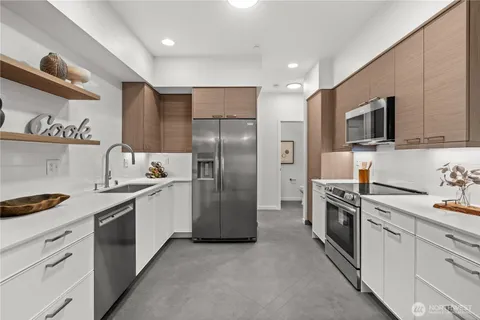 a kitchen with stainless steel appliances granite countertop a refrigerator a stove a sink and a microwave