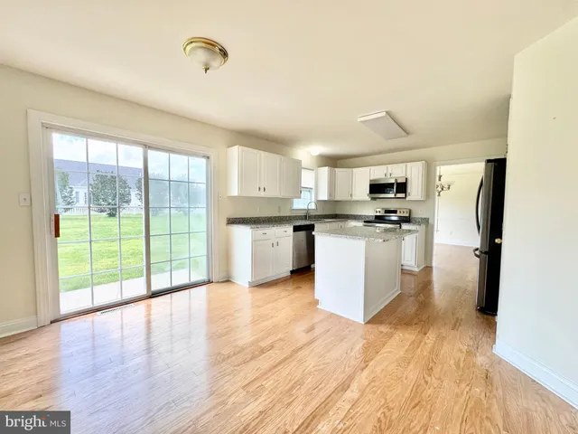 a kitchen with stainless steel appliances a stove top oven a refrigerator a sink and a wooden floor