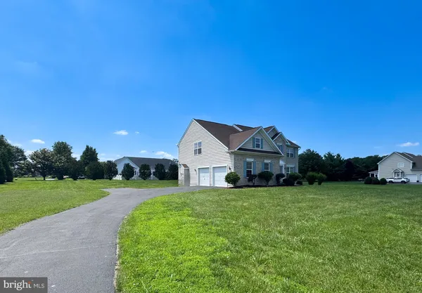 a view of a house with a big yard plants and large trees
