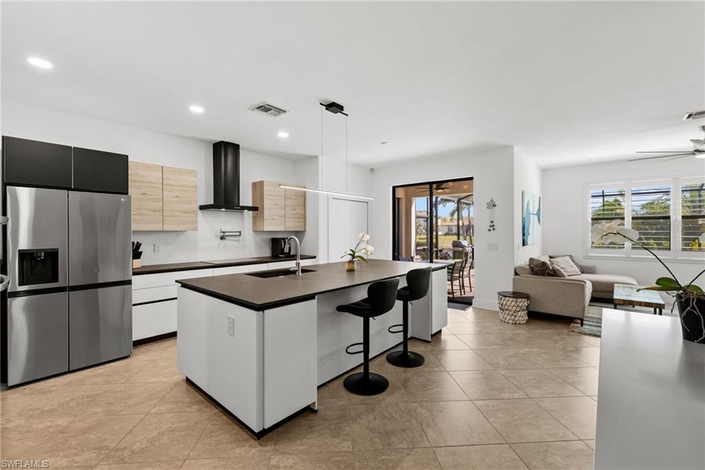 4764 Formosa Drive Naples, FL 34119 - Photo 4 of 32 a kitchen with kitchen island a stove a sink a refrigerator and couches