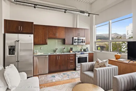 a living room with stainless steel appliances furniture and a kitchen view