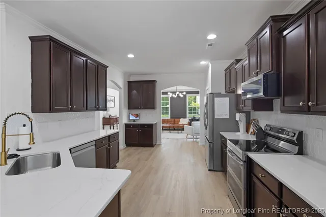 a kitchen with lots of counter top space a sink wooden floor and stainless steel appliances