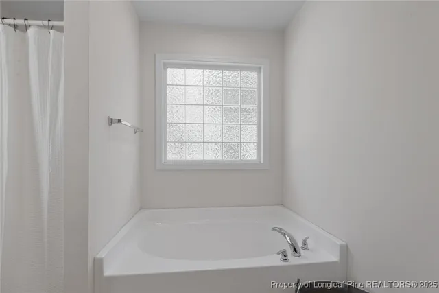 a white bath tub sitting in a bathroom next to a window
