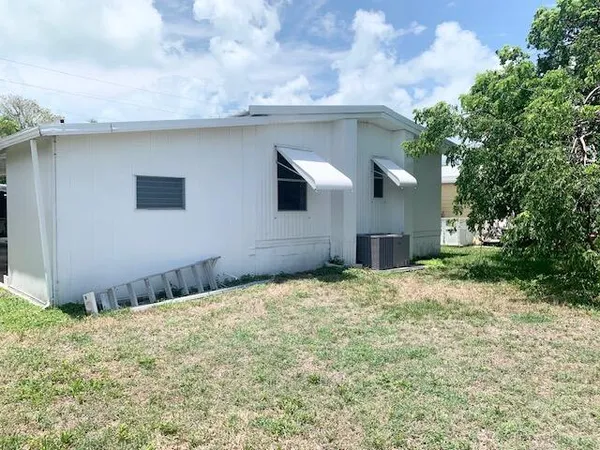 a view of a white house with a yard and a large tree