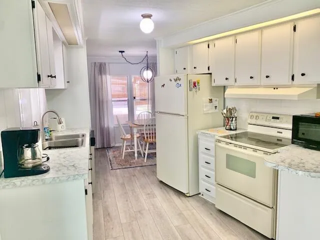 a kitchen with a refrigerator a stove a sink dishwasher and white cabinets with wooden floor