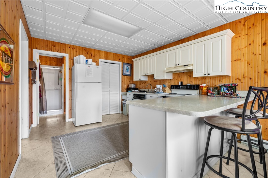 431 Cliffside Lane Seven Devils, NC 28604 - Photo 30 of 46 a kitchen with stainless steel appliances granite countertop a refrigerator a stove a sink dishwasher and white cabinets with wooden floor