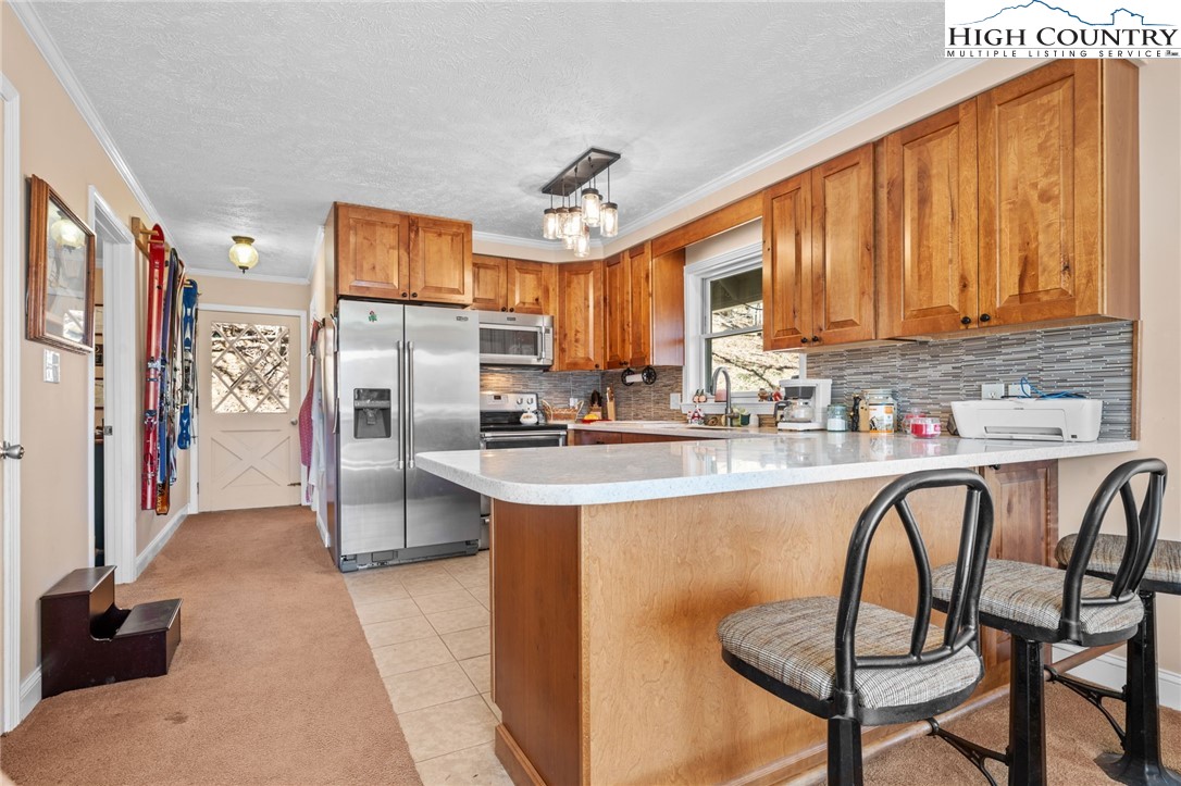 431 Cliffside Lane Seven Devils, NC 28604 - Photo 6 of 46 a kitchen with stainless steel appliances granite countertop a dining table chairs sink refrigerator and granite counter top