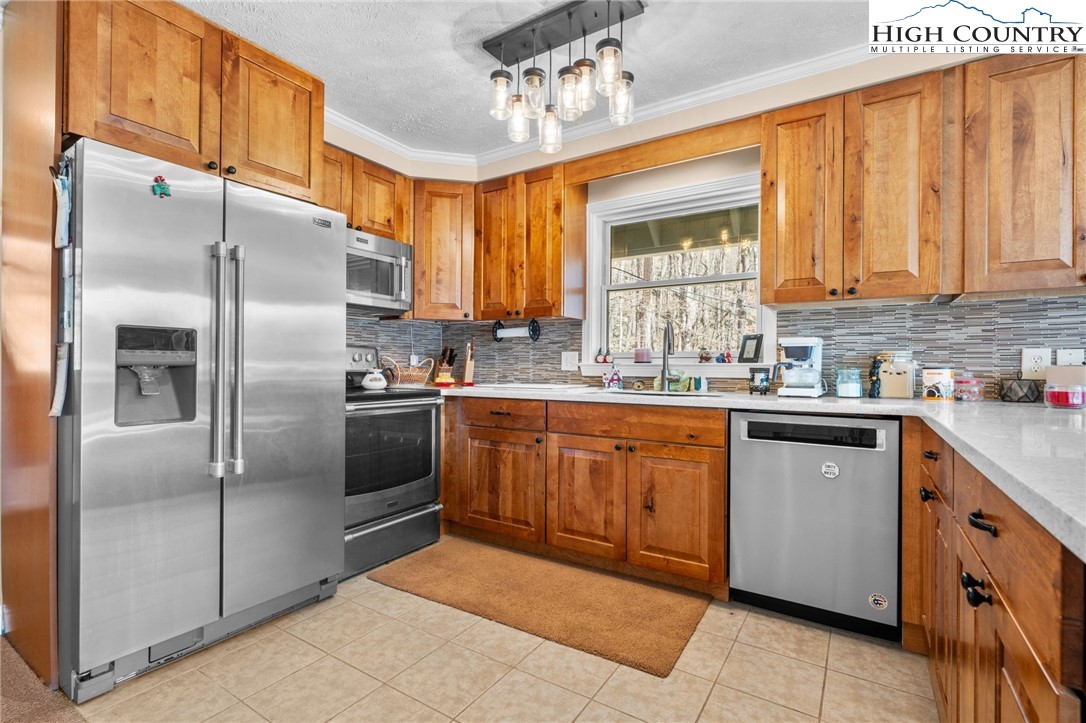 431 Cliffside Lane Seven Devils, NC 28604 - Photo 7 of 46 a kitchen with stainless steel appliances granite countertop a refrigerator a sink dishwasher a stove with wooden cabinets and floor