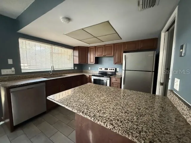 a kitchen with granite countertop a refrigerator and a sink