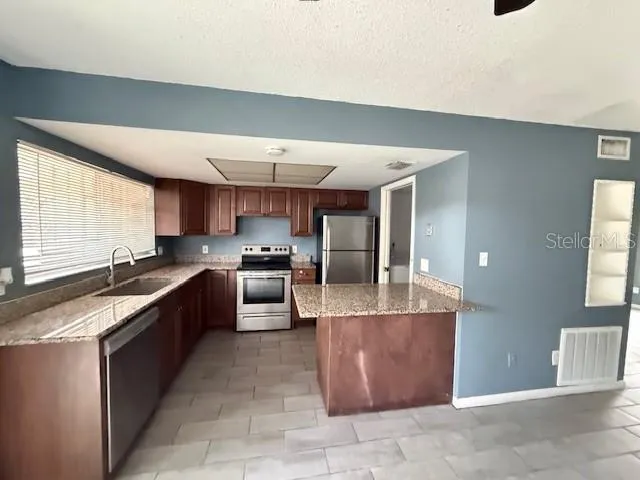 a large kitchen with a large counter top stainless steel appliances and cabinets