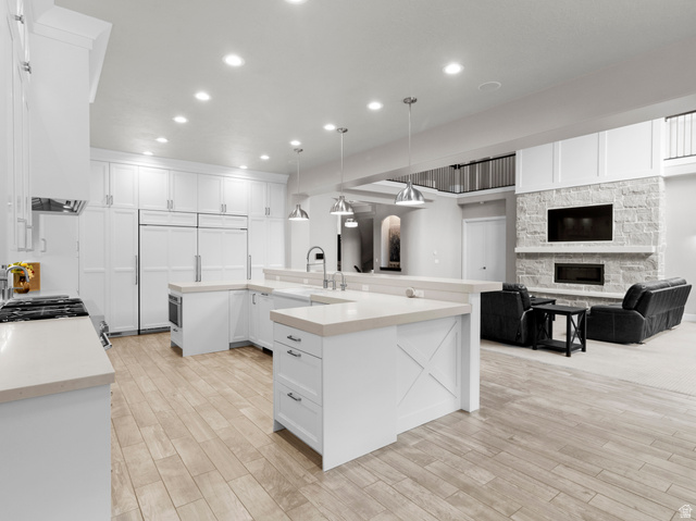 614 East High Lane Alpine, UT 84004 - Photo 75 of 75 Kitchen with a stone fireplace, open floor plan, white cabinets, light wood-style floors, and hanging light fixtures