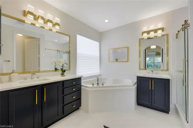 a spacious bathroom with a granite countertop double vanity sink a mirror and a bathtub