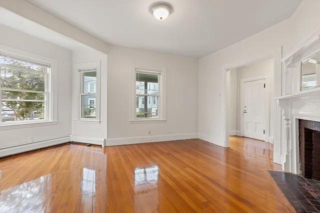 an empty room with windows and fireplace