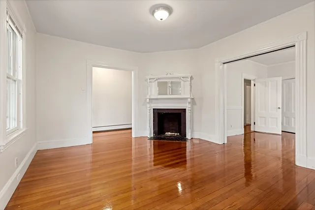 an empty room with wooden floor and fireplace