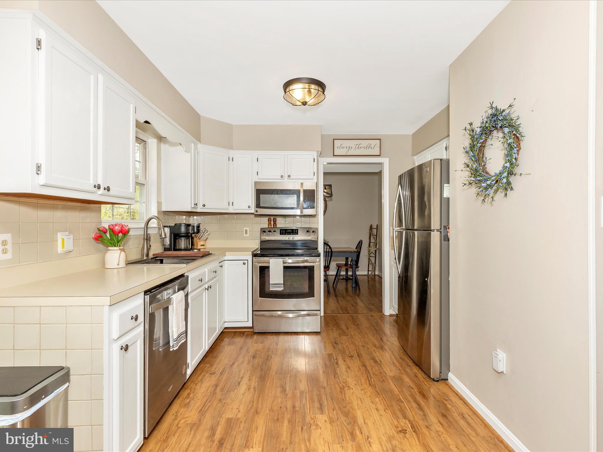 3935 Brittany Lane Hampstead, MD 21074 - Photo 15 of 55 a kitchen with granite countertop a refrigerator oven a sink dishwasher and white cabinets with wooden floor