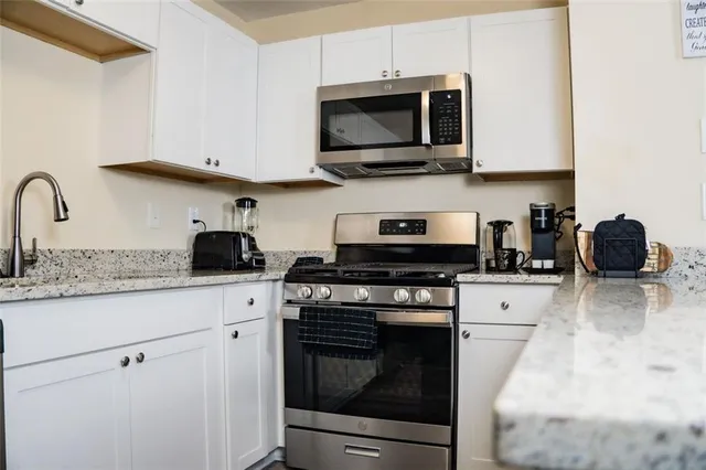 a kitchen with stainless steel appliances granite countertop a stove a microwave a sink and cabinets