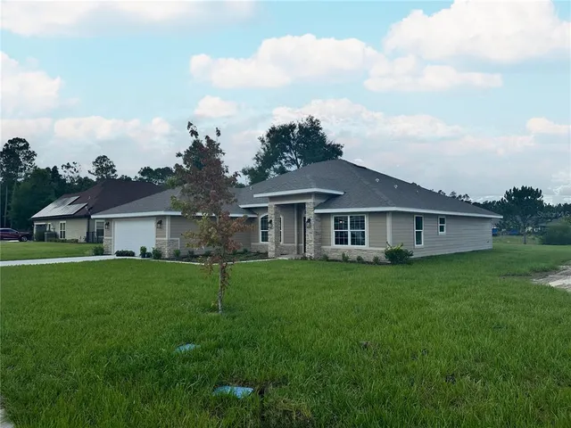 a view of a yard in front of a house with plants and large tree