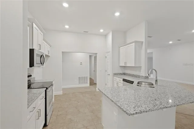 a kitchen with granite countertop a sink stove and cabinets