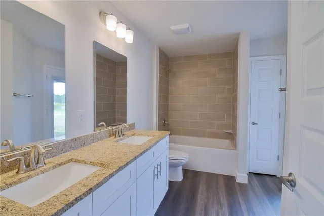a bathroom with a granite countertop sink a toilet and shower