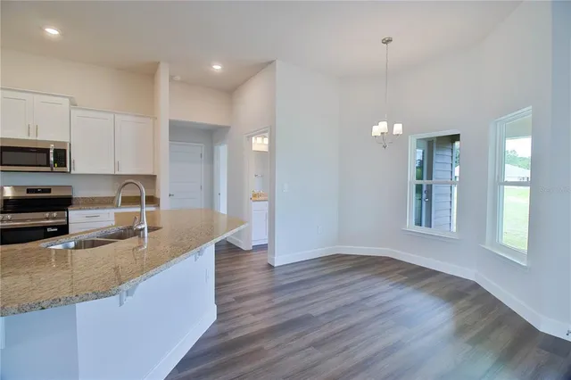 a kitchen with stainless steel appliances granite countertop a sink a stove and a wooden floors