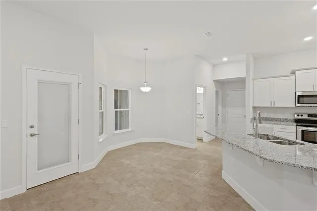 a view of a kitchen with a sink and dishwasher a refrigerator with white cabinets