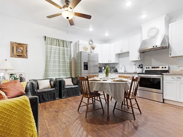 a dining room with stainless steel appliances kitchen island granite countertop a dining table chairs and a refrigerator