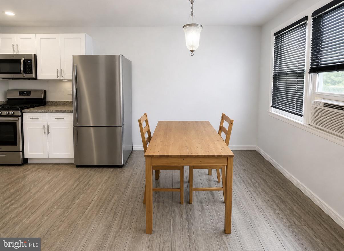 3129 Comly Road Philadelphia, PA 19154 - Photo 4 of 7 a kitchen with stainless steel appliances granite countertop a refrigerator a stove a microwave and a dining table with wooden floor