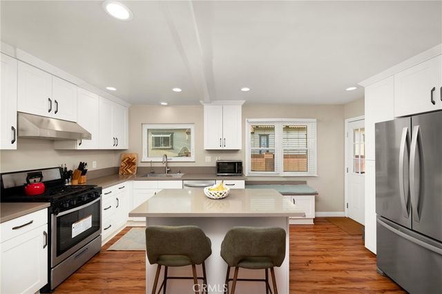 a kitchen with stainless steel appliances granite countertop a stove refrigerator a sink dishwasher and cabinets with wooden floor