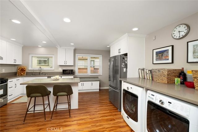 a kitchen with stainless steel appliances granite countertop a stove top oven a sink dishwasher and white cabinets with wooden floor