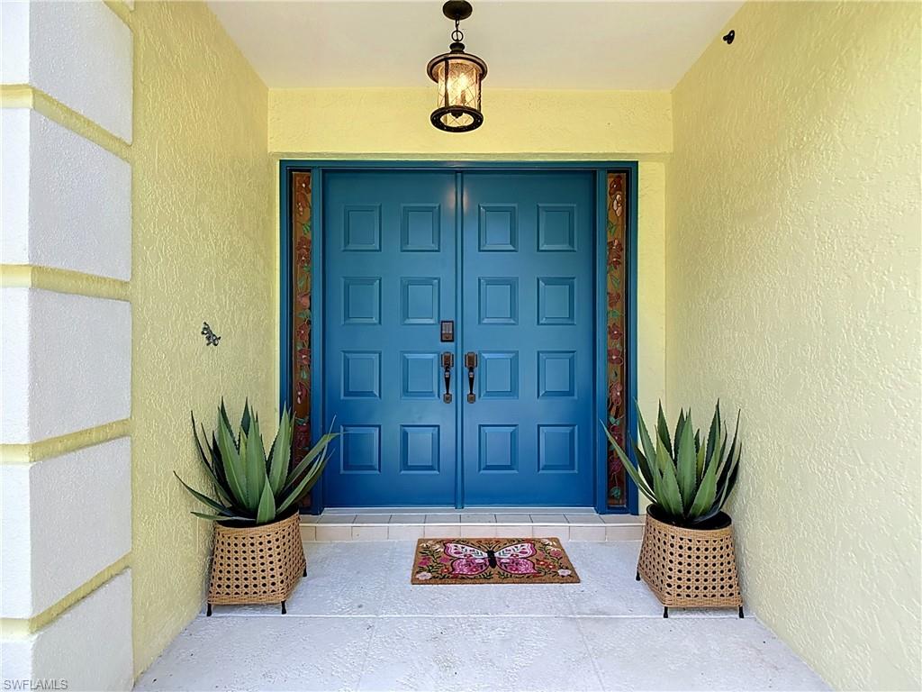 812 102nd Avenue North Naples, FL 34108 - Photo 2 of 33 Double entry doors with decorative sidelights, overhead lantern light fixture, and textured exterior wall finish
