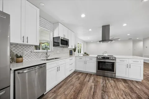a kitchen with stainless steel appliances granite countertop refrigerator sink and stove top oven