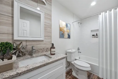 a bathroom with a granite countertop sink toilet and shower