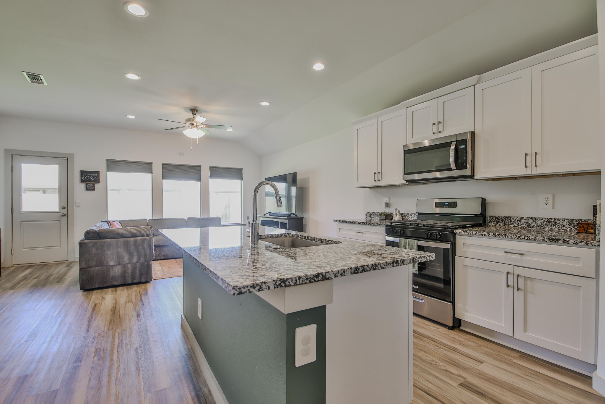7406 9th Street Lubbock, TX 79416 - Photo 28 of 54 a kitchen with stainless steel appliances granite countertop wooden cabinets a stove a sink and a microwave