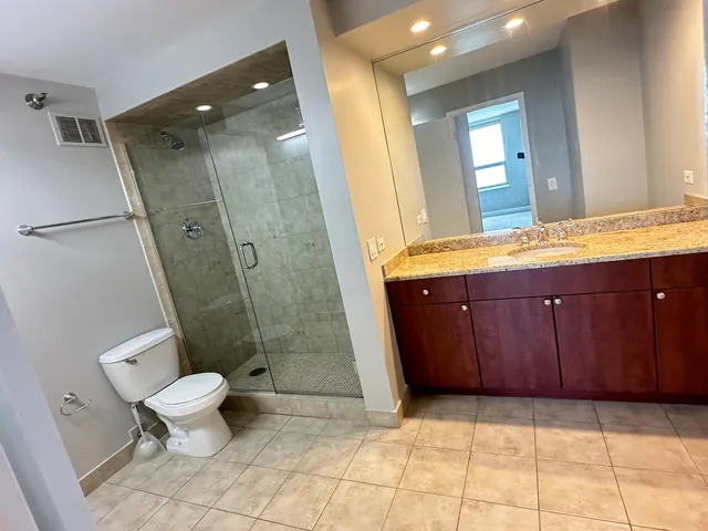 a bathroom with a granite countertop sink toilet and shower