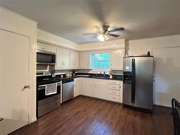 a kitchen with granite countertop a refrigerator oven a sink and wooden floor