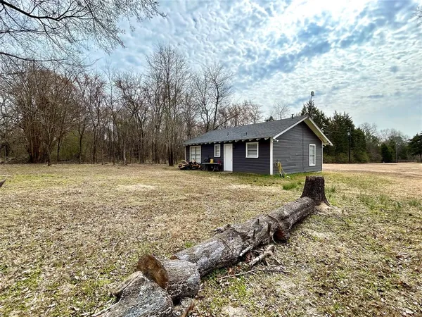 a front view of house with yard and trees in the background