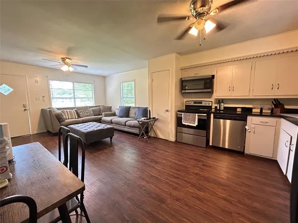 a living room with stainless steel appliances furniture and a kitchen view