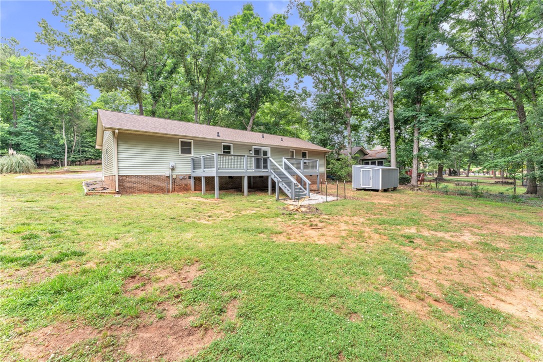 4416 Denver Cove Road Anderson, SC 29625 - Photo 24 of 31 A spacious backyard with an elevated deck offers ample outdoor living potential amidst mature trees.