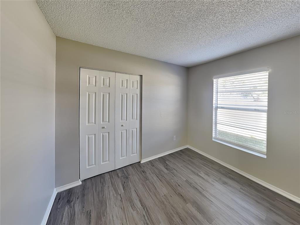 Undisclosed Address Deltona, FL 32738 - Photo 11 of 18 a view of an empty room with wooden floor and a window
