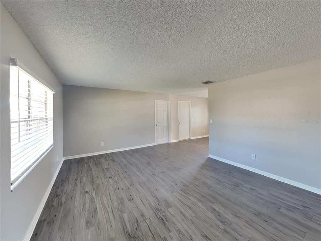 Undisclosed Address Deltona, FL 32738 - Photo 3 of 18 an empty room with wooden floor and windows