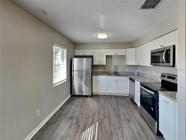 a kitchen with granite countertop a refrigerator stove top oven and sink