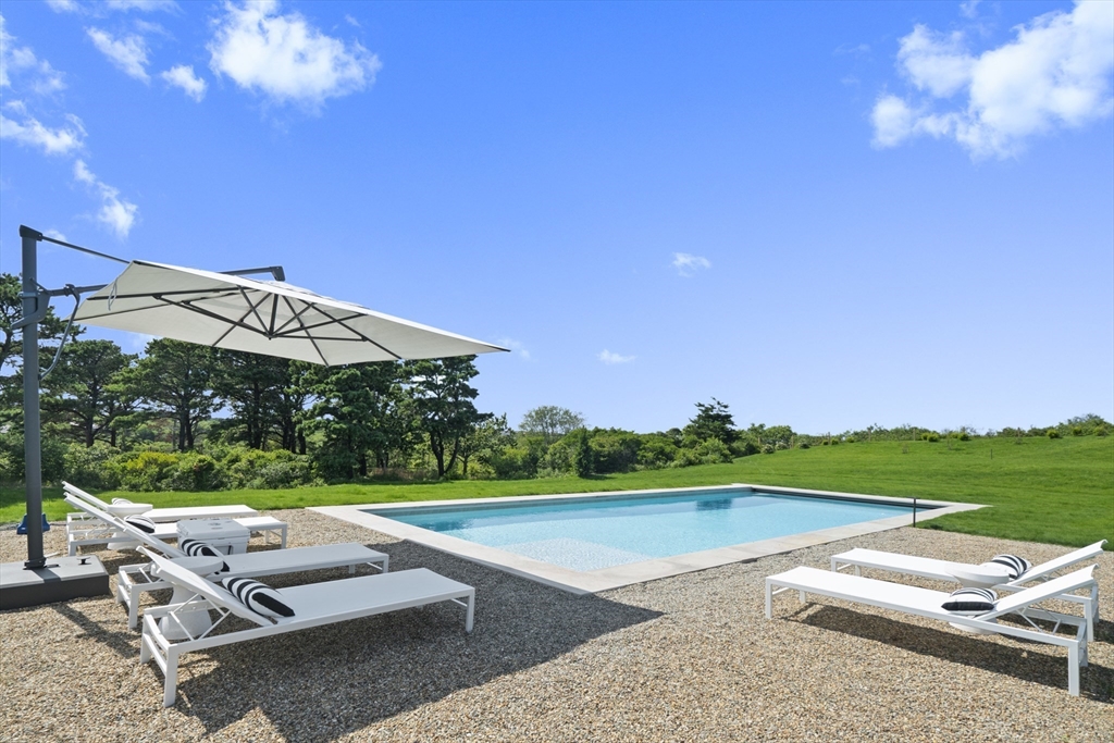 10 Maxey Pond Road Nantucket, MA 02554 - Photo 4 of 35 a view of a lawn chairs and a table and chairs under an umbrella