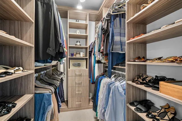 a view of walk in closet with clothes and shoes