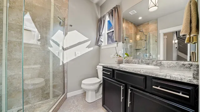 a bathroom with a granite countertop sink a toilet and a mirror