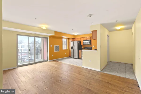 a view of an empty room with kitchen and a window
