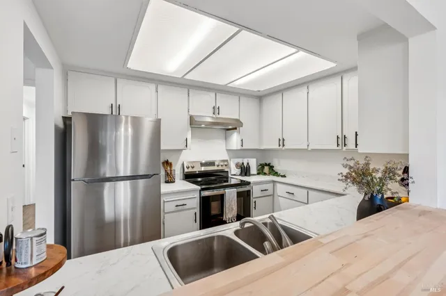 a kitchen with a refrigerator sink and white cabinets