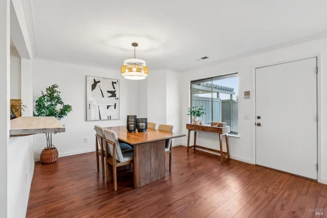 a dining room with wooden floor a chandelier a wooden table and chairs